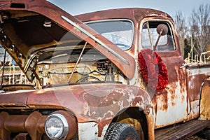 Red christmas wreath hanging on the mirror of antique truck