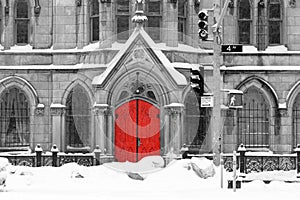 Red church door in snowy black and white winter street scene on 4th Avenue in the East Village of New York City