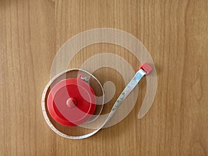 Red circle measure tape with white line on wooden texture