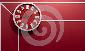 Red circle wall clock decorated with domino pieces hanging against red wall with graphic line background