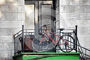 Red city bicycle parked in front of an old apartment door next to the staircase