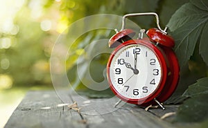 Red classic alarm clock in the garden, save time, daylight saving concept