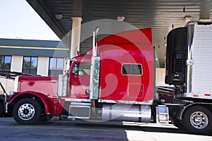 Red classic big rig semi truck and reefer trailer photo