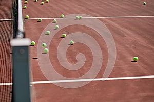 Red-clay tennis court with sport equipment and tennis balls on it.