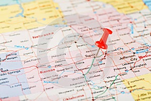 Red clerical needle on a map of USA, Kansas and the capital Topeka. Close up map of Kansas with red tack