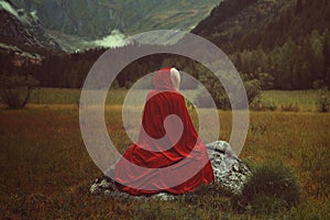 Red cloak woman alone on a rock