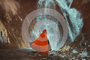 Red cloaked figure in front of a mighty waterfall photo