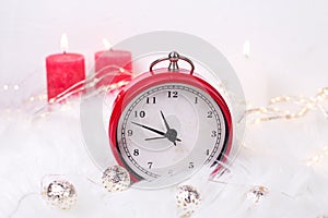 Red clock - symbol of New Year, fairy lights and birning candl