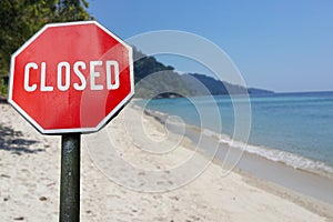 Red closed sign on beach background. COVID 19 pandemic quarantine. Cancelled vacation, travel, holiday plans because of corona