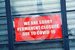 Red closed sign in the window of a shop displaying permanent closure