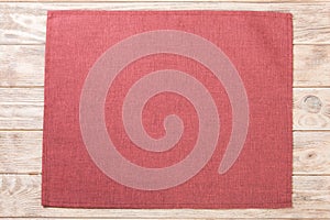 Red cloth napkin on brown rustic wooden background top view with copy space