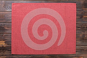Red cloth napkin on dark rustic wooden background top view with copy space