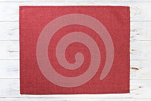 Red cloth napkin on white rustic wooden background top view with copy space