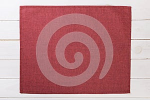 Red cloth napkin on white rustic wooden background top view with copy space