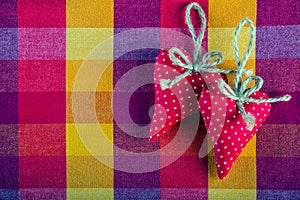 Red cloth two handmade hearts on checkered cloth napkin.