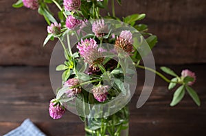 Red clover in a jar on wooden table