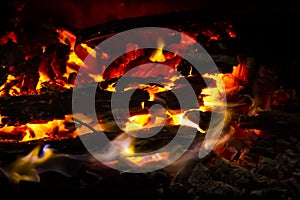 Red coals with fire on black background. Burning coals and wood in fire. Burning wood to keep warm and heat. Glowing embers in hot