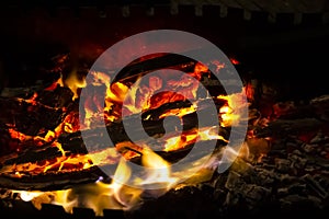 Red coals with fire on black background. Burning coals and wood in fire. Burning wood to keep warm and heat. Glowing embers in hot