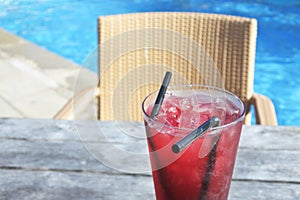 Red cocktail drink with ice served on a poolside table in a tropical resort