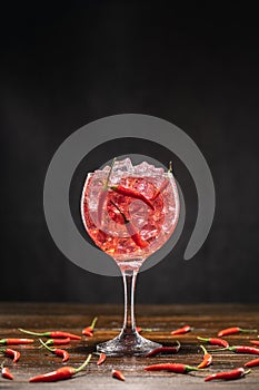 Red cocktail in a glass with ice and chili peppers. Valentine`s Day Concept