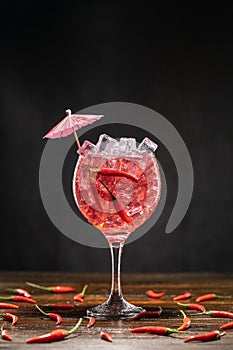 Red cocktail in a glass with ice and chili peppers. Valentine's Day Concept