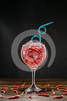 Red cocktail in a glass with ice and chili peppers. Valentine's Day Concept