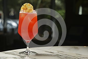 Red cocktail glass with ice cubes and dry pineapple slice