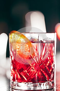 Red cocktail in glass isolated on blurred restaurant background.