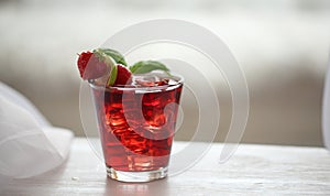 Red cocktail with ice, decorated with mint leaf, lime and trawberry on light background