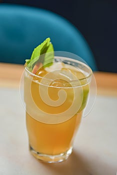 Red cocktail with ice served in a glass on wooden table with blurred restaurant background. Refreshing summer beverage