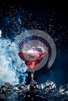 Red cocktail with ice vapor, blue background