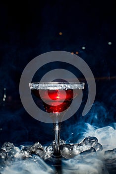 Red cocktail with ice vapor, blue background