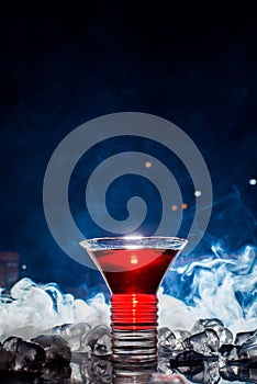 Red cocktail with ice vapor, blue background