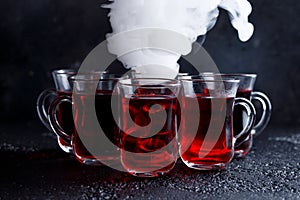 Red cocktail with ice vapor. red cold tea with steam on a black background.