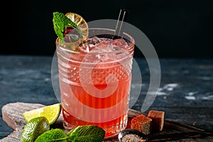 Red cocktail with juice, grenadine, ice, mint and lime on glass