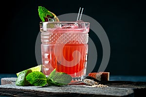 Red cocktail with juice, grenadine, ice, mint and lime on glass