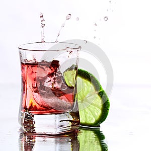 Red cocktail with lime on white