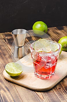 Red cocktail with lime on a wooden table