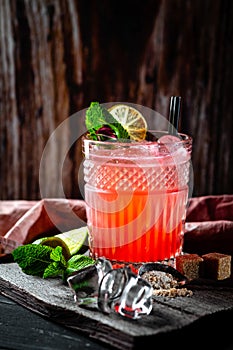 Red cocktail with rum, juice, grenadine, ice, mint and lime on glass