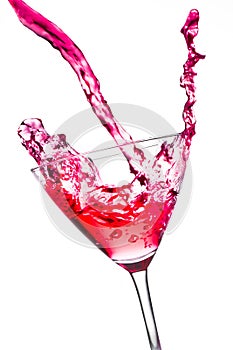 Red cocktail with splashing in the tilted glass