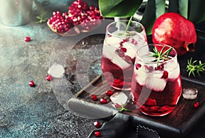 Red cocktail vodka pomegranate juice, with ice and rosemary, bar tools, blue bar counter background, top view