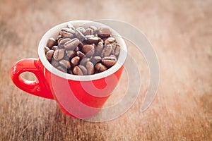 Red coffee cup with coffee beans on wooden table