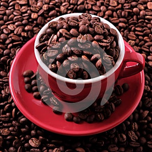 Red coffee cup filled pile heap with roasted beans closeup