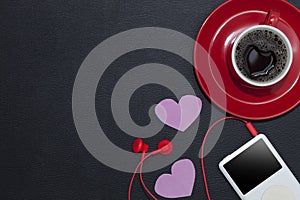 Red coffee cup with music player and red earphone on black leath