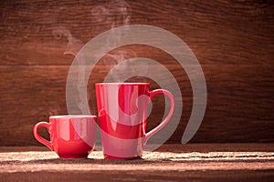 Red coffee cup with smoke stream on wooden table