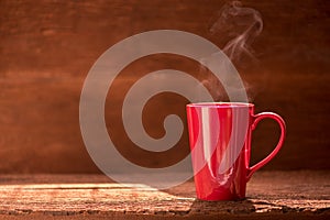 red coffee cup with smoke stream on wooden table under moring sunlight