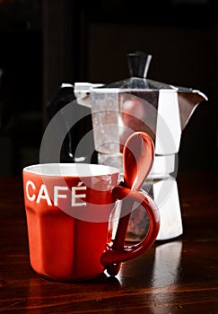 Red coffee cup and vintage coffeepot on dark wooden table