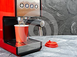 Red coffee machine fills a red paper cup. Coffee to go.