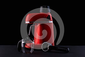 A red coffee machine with a glass pitcher against a black background. Still-life with kitchen utensils for making espresso