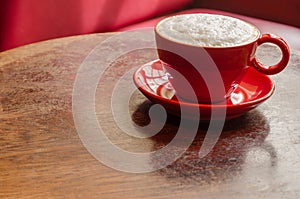 Red coffee mug with frothed milk on an old wooden table